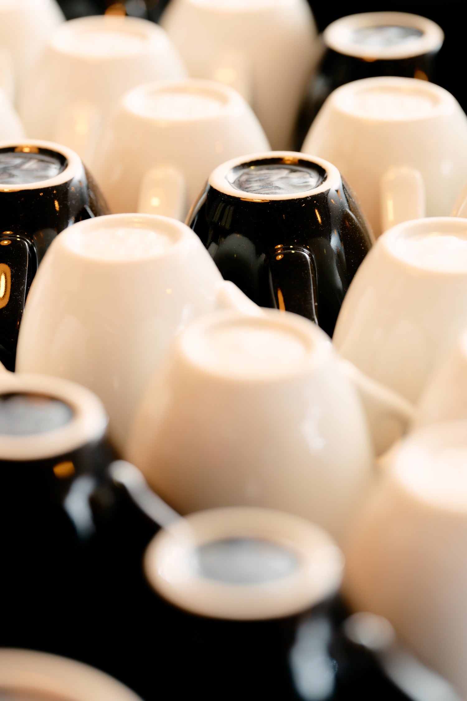 Weiße und schwarze Espressotassen, die umgedreht auf der Siebträgermaschine stehen, so daß sie heiß werden